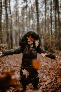 Kaboompics - A woman throws up the autumn brown leaves