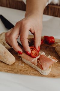 Kaboompics - Woman Topping Prosciutto Bread with a Tomato Slice