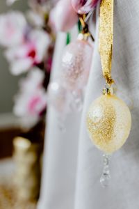 Kaboompics - Pink, White and Gold Easter Egg Ornaments Hanging from Ribbon against Spring Blossoms