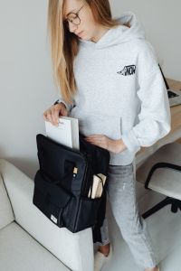 Kaboompics - Close Up of Teenager Packing Books into Black Backpack