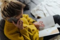 Kaboompics - Woman Reading on Sofa During a Phone Call, Open Book on Her Lap