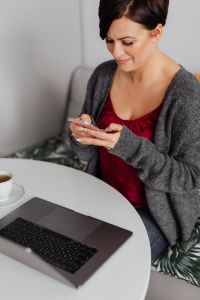A brunette woman works with a laptop and a phone