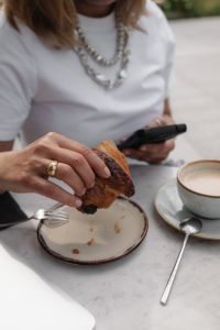 Kaboompics - Woman Eating a Croissant with Coffee at a Cafe