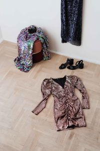 Kaboompics - colored sequin dresses and boots lie on a wooden parquet, blue dress hang on the white wall
