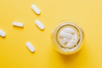 Kaboompics - Yellow Medicine Bottle with Scattered White Pills from Above