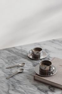 Kaboompics - Two Chrome Espresso Cups with Spoons on Marble and a Neutral Book, Minimal Coffee Styling