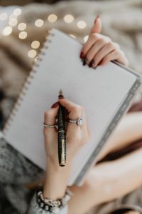 Kaboompics - Writing in a notebook lying in bed, with coffee, candles, and gingerbreads