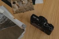 Kaboompics - Fujifilm X100VI Camera and Printed Photos on Wooden Desk