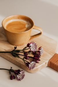 Kaboompics - Warm Coffee and Burgundy Astrantia on a Wooden Serving Board, Vertical Still Life