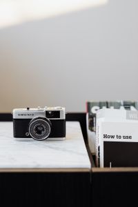 Kaboompics - Vertical Vintage Film Camera and Books on Marble with Large Neutral Copy Space