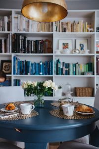 Kaboompics - Round breakfast table with white flowers by the bookcase