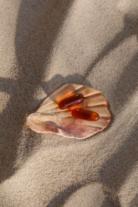 Kaboompics - Three Supplement Capsules in a Shell on Sand