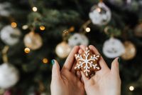 Kaboompics - Woman holds a gingerbread cookie, Christmas tree background