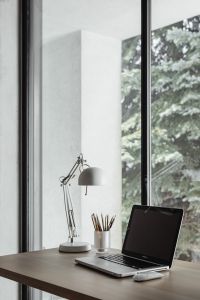 Kaboompics - White Adjustable Desk Lamp and Pencils beside a Dark-Screen Laptop and Window
