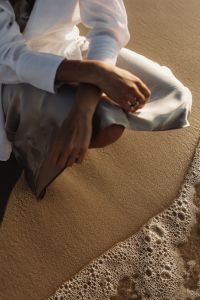 Kaboompics - Woman Sitting by Waves in White Shirt and Satin Skirt
