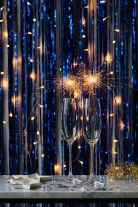 Kaboompics - Sparkler Burst Above Champagne Glasses on a Metallic Fringe Background