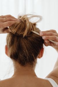 Kaboompics - Woman Creating a Messy High Bun with a Hair Stick, DIY Updo and At-Home Hairstyling