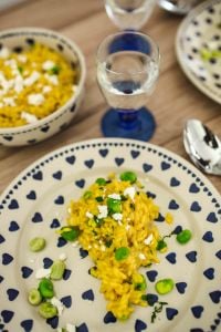 Kaboompics - Yellow rice with greens on a cute plate with blue hearts and a table decorated with flower petals