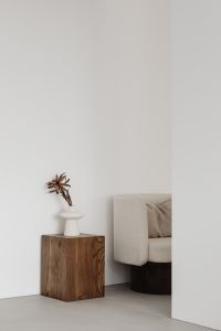 Kaboompics - Neutral Living Room Corner with Walnut Pedestal, Sculptural Vase and Armchair Copy Space