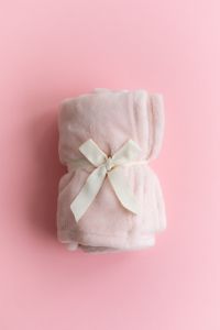 Kaboompics - Folded Pink Blanket Tied With Ribbon On Pink Background