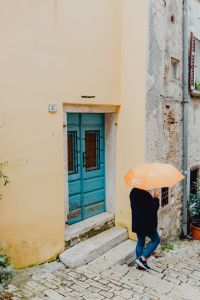 Kaboompics - Woman with Yellow Umbrella Passing a Blue Door in Rovinj Old Town