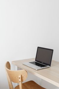 Kaboompics - Silver Laptop on Pale Wood Desk with Wooden Chair and White Wall, Minimal Workspace Mockup