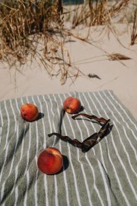 Kaboompics - Three Peaches and Sunglasses on a Striped Towel