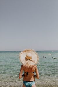 Kaboompics - Back View of Woman Wading in Clear Water with Raffia Hat and Copy Space