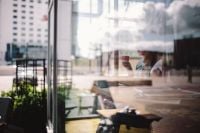 Kaboompics - Woman Reading with Coffee in a Coffee Shop Window Reflection