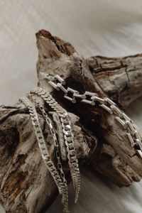 Kaboompics - Layered Silver Chain Necklaces Draped over Driftwood