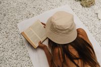 Kaboompics - Top View of Woman Reading on a White Towel in a Straw Hat