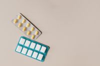 Kaboompics - Pill Blister Packs with Yellow Tablets and Teal Empty Tray on Beige, Medication Copy Space
