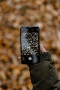 Kaboompics - A woman takes a picture with her iPhone X in the autumn forest