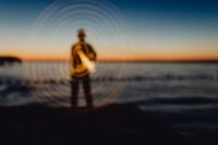 Kaboompics - Light painting. The man waving fairy lights at the sea at sunset.