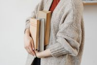 Kaboompics - Young Woman in a Wool Sweater Holding a Stack of Books for Cozy Lifestyle Content