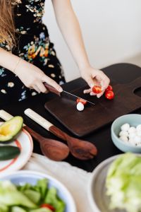 Kaboompics - Home Cook Slicing Cherry Tomatoes on a Dark Cutting Board