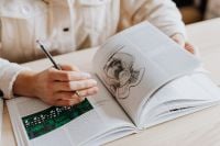 Kaboompics - Woman Drawing in Open Book with Pencil at Desk