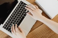 Kaboompics - Hand Typing on Laptop Keyboard Beside Blank Notebook, Overhead Work from Home Desk