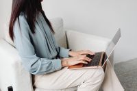 Kaboompics - Close-Up of Hands Typing on a Laptop in a White Armchair