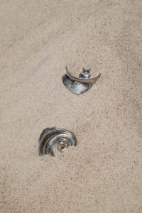 Kaboompics - Silver Spiral Earrings Partially Buried in Sand