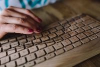 Kaboompics - Closeup of female hands typing text on a wireless wooden keyboard