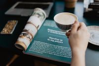 Kaboompics - Person Holding Coffee Beside a Rolled Magazine