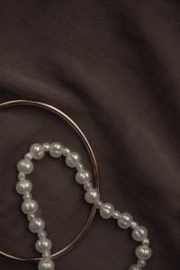 Kaboompics - Pearl Bead Bracelet and Gold Hoop on Dark Fabric