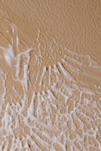 Kaboompics - Close-Up of Raised White Cream Swirls on a Tan Textured Background