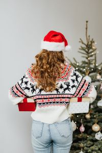 Kaboompics - Woman in Christmas Sweater Carrying Gift Boxes Behind Her Back