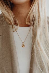 Kaboompics - Gold Pendant Necklace Against a White Ribbed Top
