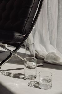 Kaboompics - Glass Water Carafe and Single Drinking Glass Beside Black Lounge Chair