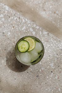 Kaboompics - Top-Down Cucumber and Lime Detox Water with Ice on Diagonal Terrazzo Steps, Textured Summer Drink Background