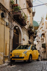 Kaboompics - Yellow Fiat 500 in a Narrow Cobblestone Alley Beside an Arched Doorway