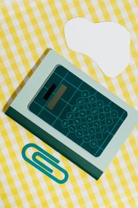 Kaboompics - Vertical Flat Lay of a Green Calculator and Paper Clip